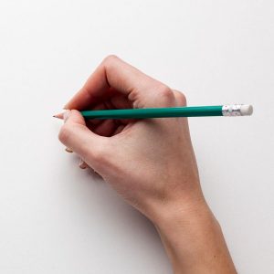 top view of hand holding pencil with copy space